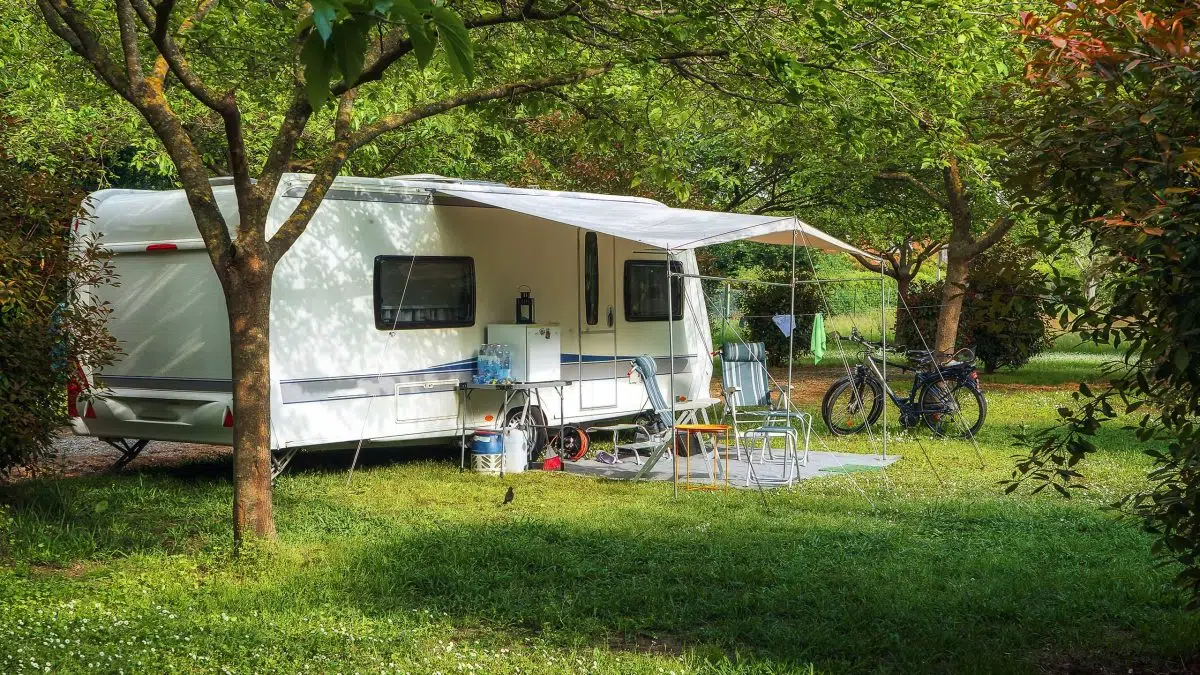 Ein Wohnwagen mit einer Markise auf einem grünen Campingplatz.